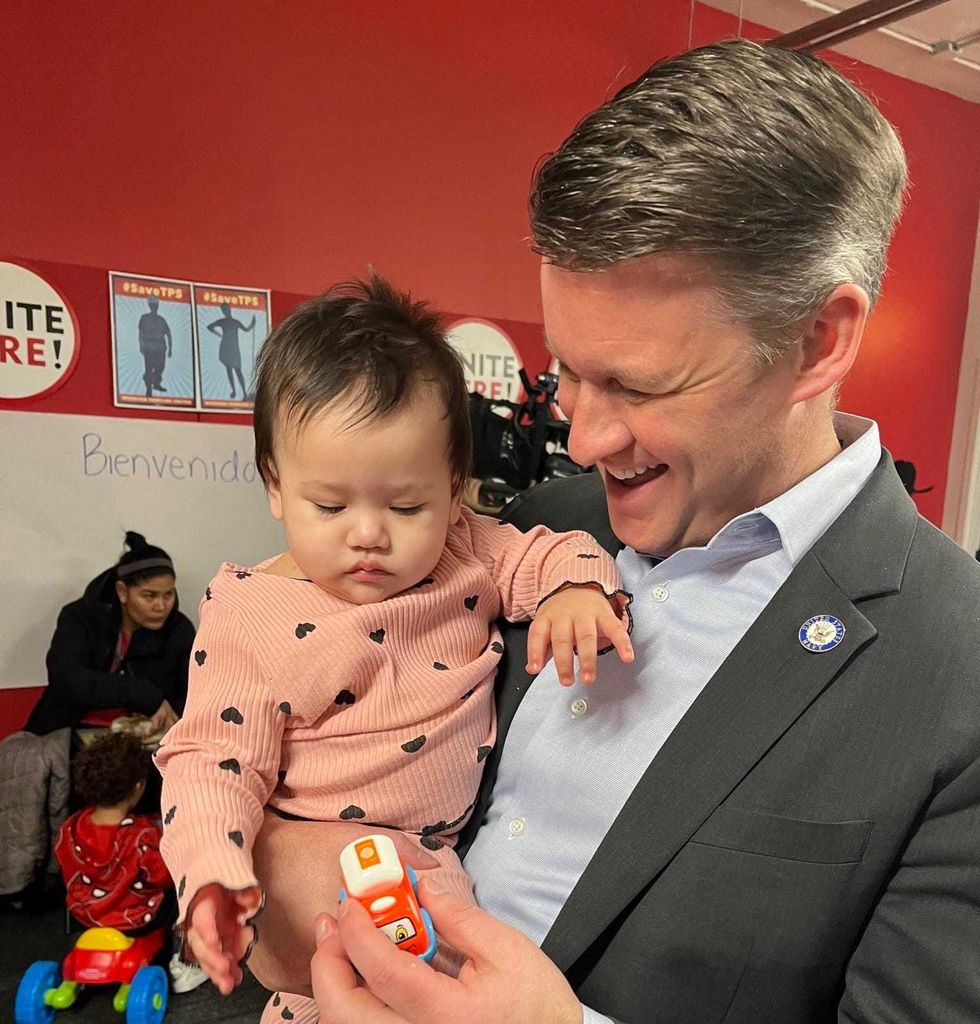 Ald. Bill Conway holds a baby at a free legal aid clinic for migrants that took place in Chicago