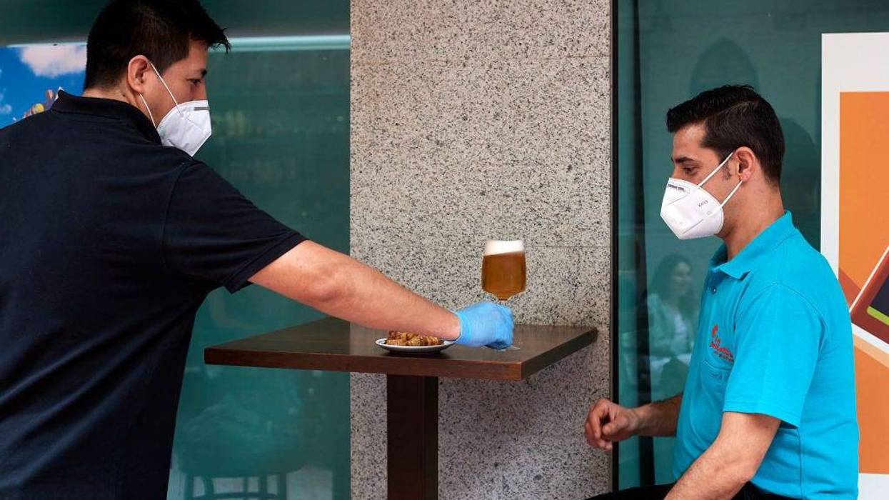 Aldovladimir Trigo serves a beer to a client at the Casa Dani restaurant on May 25, 2020 in Madrid, Spain. Some parts of Spain have entered the so-called "Phase One" or "Phase Two" transitions from its coronavirus lockdown, allowing many shops to reopen as well as restaurants who serve customers outdoors. Locations that were harder hit by the coronavirus (COVID-19), such as Madrid and Barcelona, remain in a stricter quarantine.