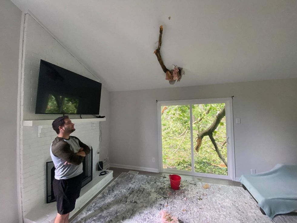 Alec Barmore looks up at the tree limb that crashed through his ceiling after a powerful storm the morning of June 9, 2022, in Blackwood, New Jersey.