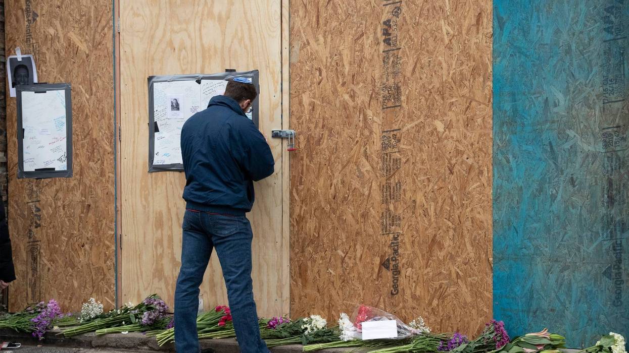 Alex Seligson pens a note of condolence Friday, Dec. 13, 2019 in Jersey City, N.J. at the boarded up kosher grocery store where three people and two gunmen were killed on Tuesday.