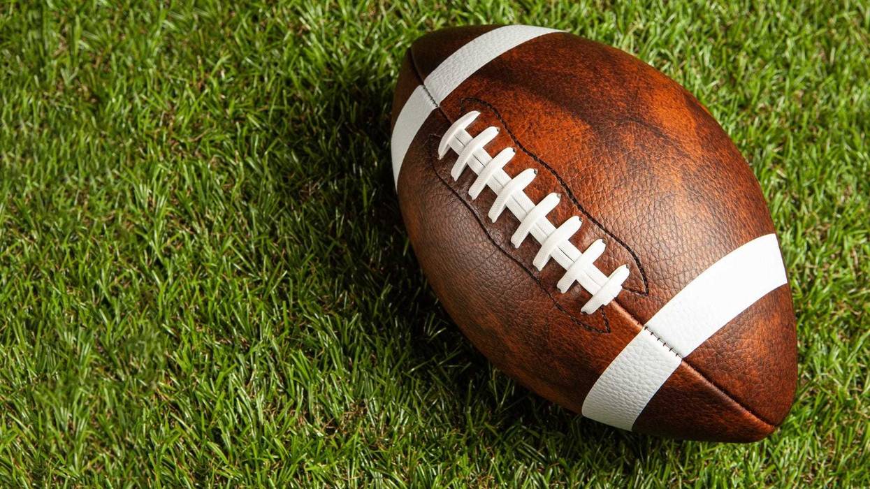 American football ball on green grass field background