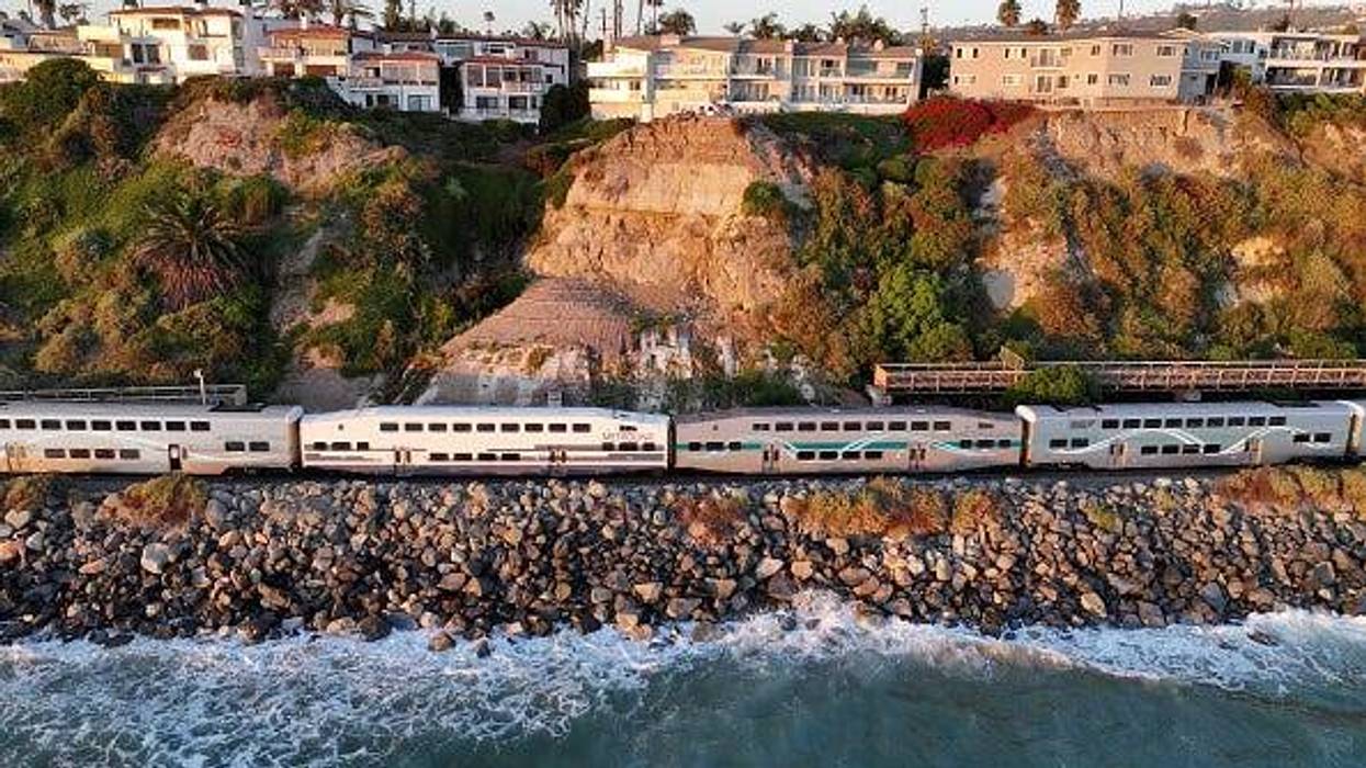 An aerial view of a Metrolinertrain passing along eroding coastline
