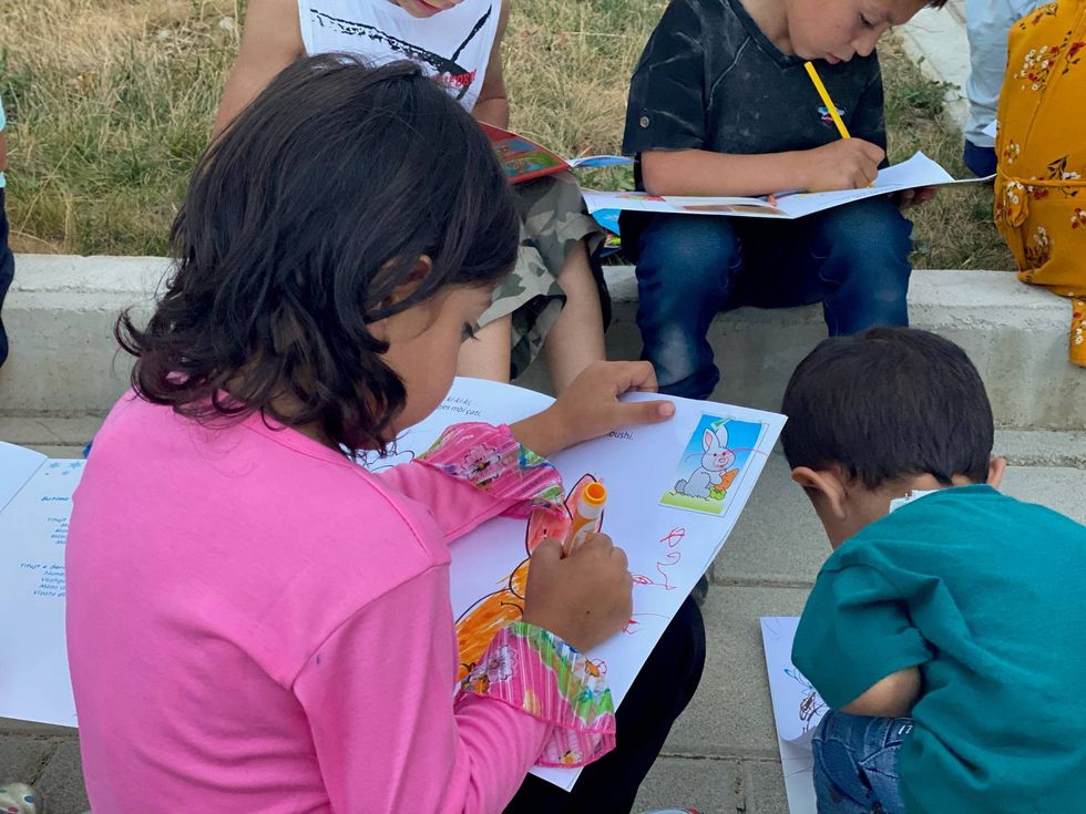 an Afghan girl colors after getting processed and checked in in Albania. Spirit of America is supporting the food, shelter, medical, and basic needs of 121 Afghans in Albania.