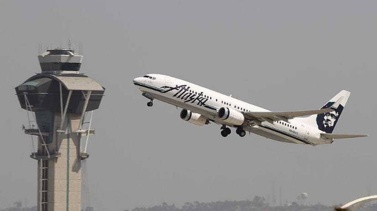 An Alaska Airlines jet passes the air traffic control tower at LAX.
