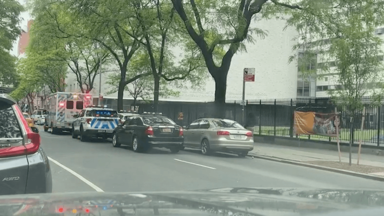 An ambulance and police car arrive at the scene in front of 439 W 49th St., which houses Business of Sports School, Urban Assembly Gateway School for Technology, and Stephen T. Mather Arts and Craftsmanship High School.