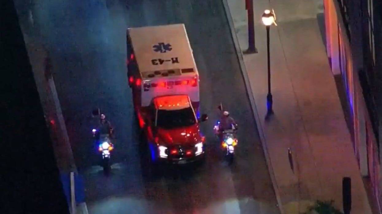 An ambulance is escorted by a pair of police officers on motorcycles.