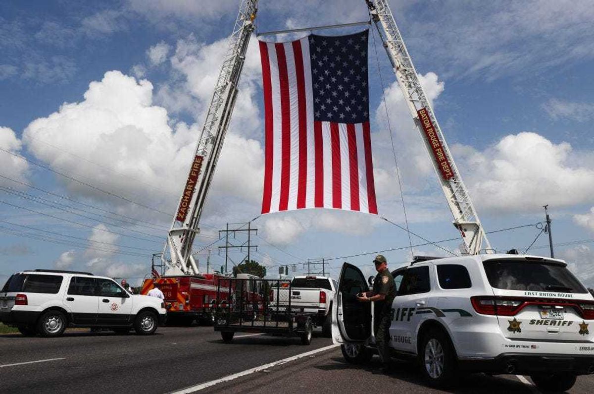 An American flag is displayed along the funeral procession route for late Baker Police Department officer Lt. DeMarcus Dunn, who passed away from complications caused by COVID-19, near Louisiana National Cemetery on August 20, 2021 in Zachary, Louisiana. Dunn, who was also a U.S. Air Force veteran and youth mentor, passed away the day before he was set to marry and leaves behind his fiancé and three children, aged 1, 5, and 13. The Louisiana Department of Health today reported 2,999 people hospitalized and 56 more confirmed deaths due to the coronavirus. (Photo by Mario Tama/Getty Images)