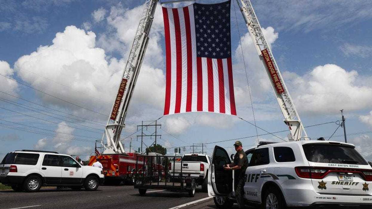 An American flag is displayed along the funeral procession route for late Baker Police Department officer Lt. DeMarcus Dunn, who passed away from complications caused by COVID-19, near Louisiana National Cemetery on August 20, 2021 in Zachary, Louisiana. Dunn, who was also a U.S. Air Force veteran and youth mentor, passed away the day before he was set to marry and leaves behind his fiancé and three children, aged 1, 5, and 13. The Louisiana Department of Health today reported 2,999 people hospitalized and 56 more confirmed deaths due to the coronavirus. (Photo by Mario Tama/Getty Images)