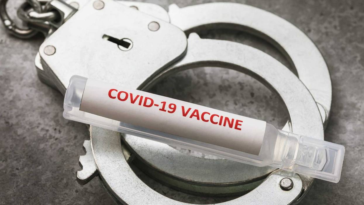 An ampoule with a covid-19 pandemic vaccine and handcuffs