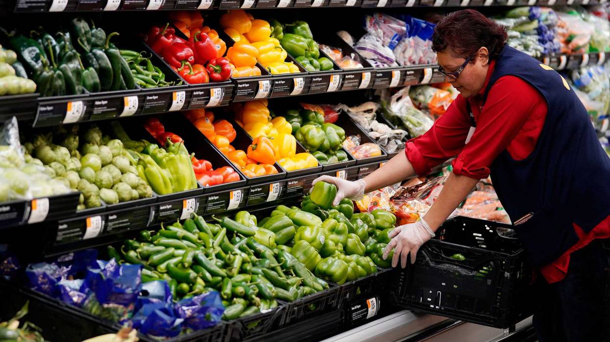 An associate restocks fresh vegetables at a Walmart Supercenter.