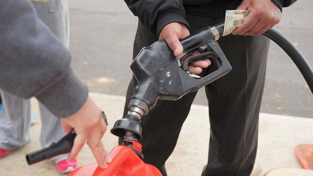 An attendant fills gas canisters as people wait in line at a Shell gas station on November 2, 2012 in Matawan, New Jersey.
