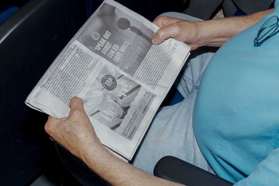 An attendee holds a newspaper about Con Edison rate hikes at a community meeting regarding energy bills