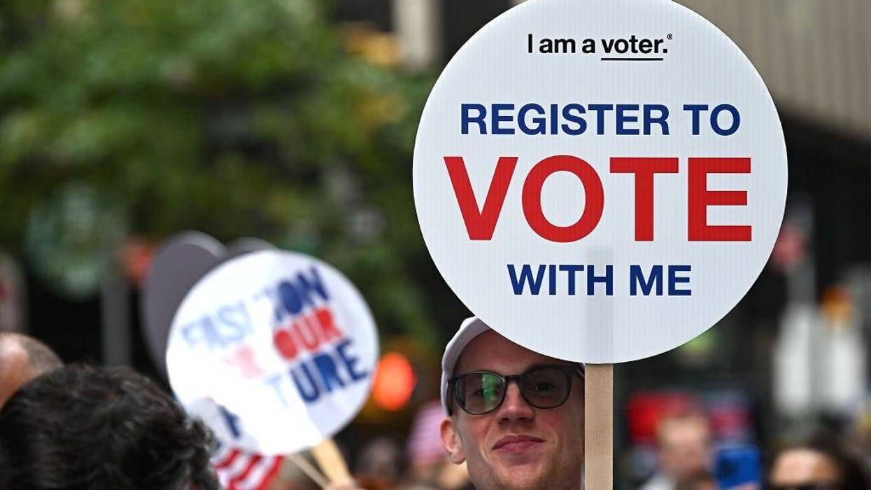 An attendee holds a "Register to Vote" sign at Fashion For Our Future March