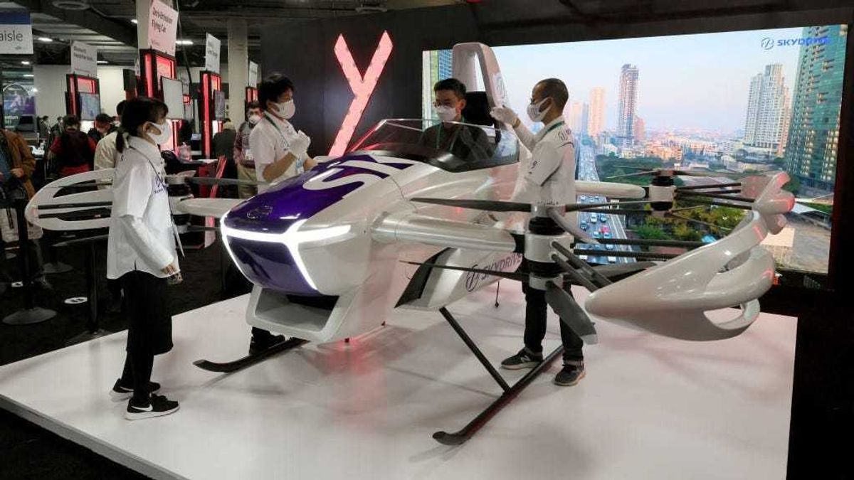 An attendee poses for photos in a protoype SkyDrive SD-03 ultra-light, compact flying vehicle that requires no runway at CES 2022 at The Venetian Las Vegas on January 5, 2022 in Las Vegas, Nevada.