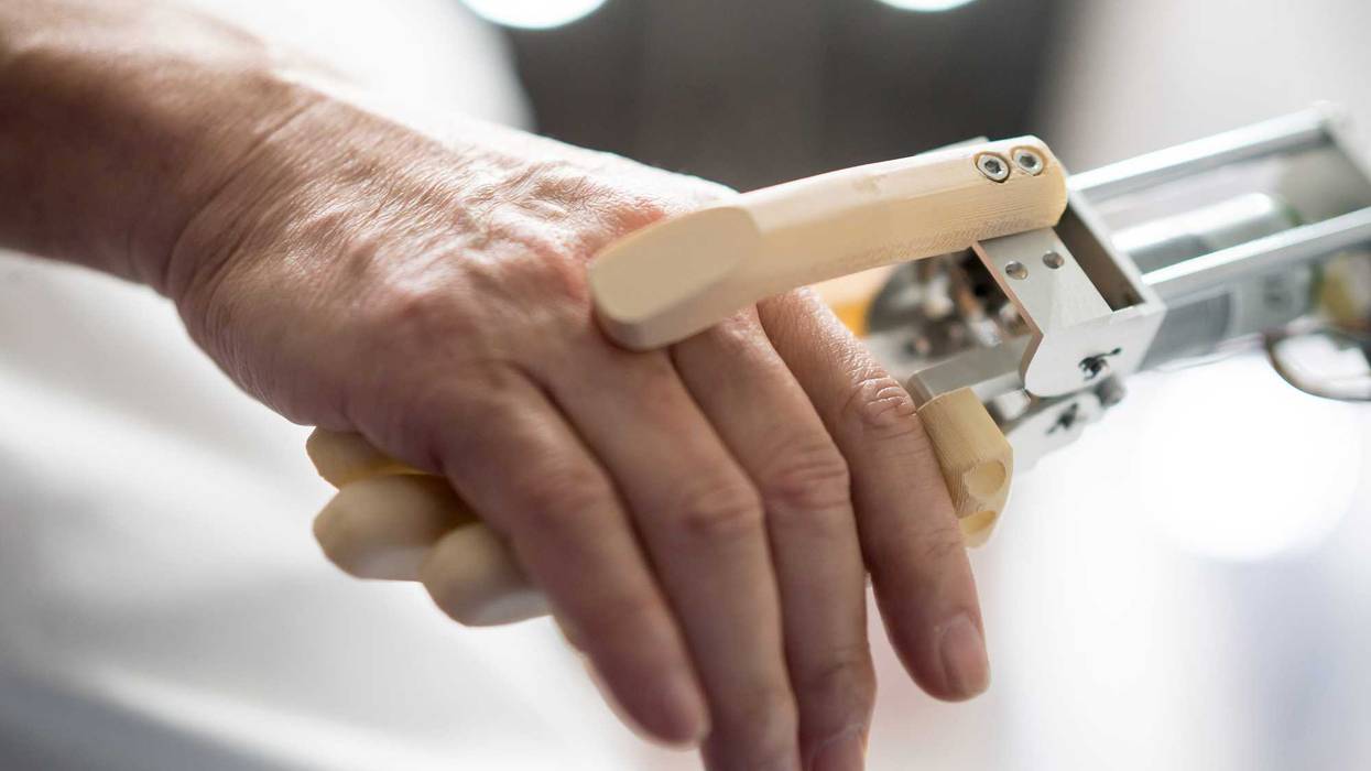 An attendee shakes hands with a robotic arm during the Japan Robot Week 2022 event on October 19, 2022 in Tokyo, Japan.