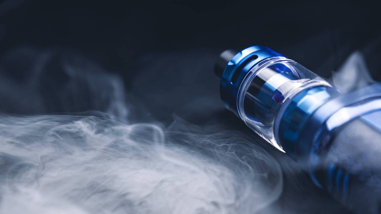 An electronic cigarette for smoking nicotine on a black background in smoke