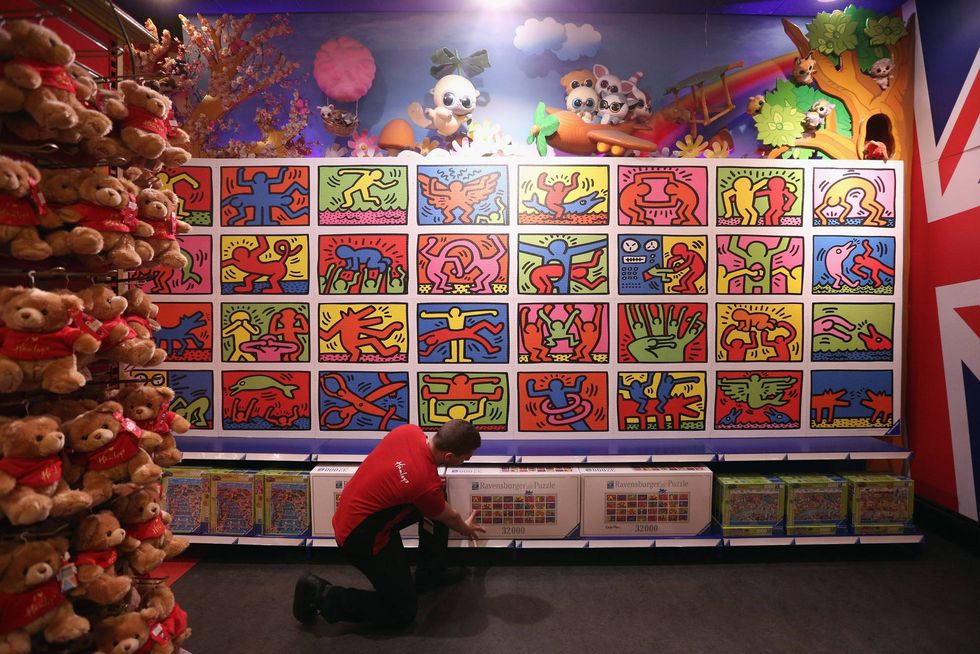 An employee adjusts a box for the 32,256-piece Keith Haring jigsaw, beneath the completed puzzle, in Hamleys toy shop on June 27, 2013, in London, England.