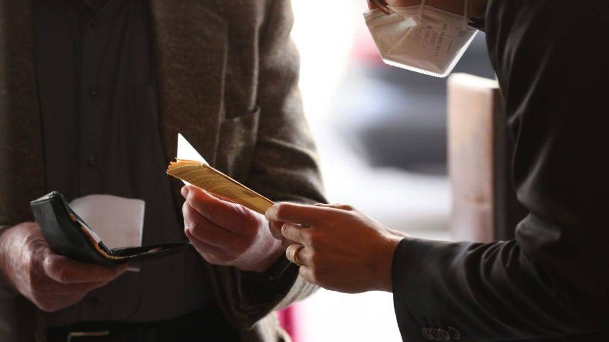 An employee of Deutsche Oper Berlin checks the vaccination certificate of a guest arriving for the premiere performance of "Das Rheingold" during the coronavirus pandemic on June 12, 2021 in Berlin, Germany.