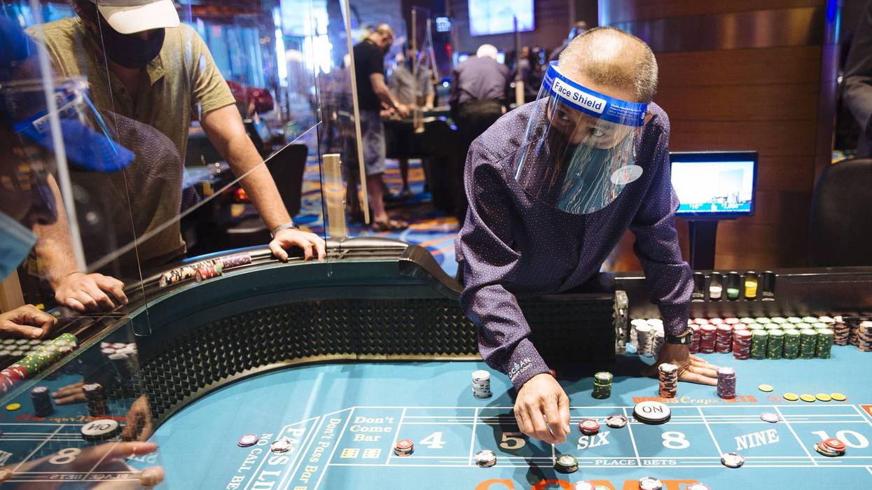 An employee wearing a protective mask and face shield speaks to a visitor at a craps table at the Ocean Casino Resort in Atlantic City.