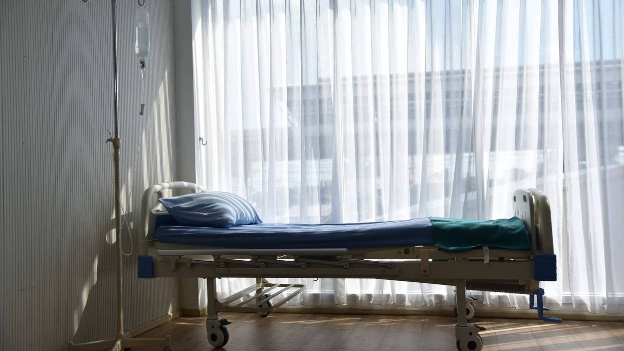 An empty patient bed in a hospital room.