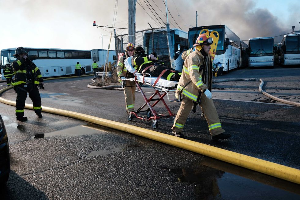 An injured firefighter is taken away on a stretcher as firefighters and other emergency personnel work to control a large fire in the Brooklyn neighborhood of Red Hook on December 13, 2022