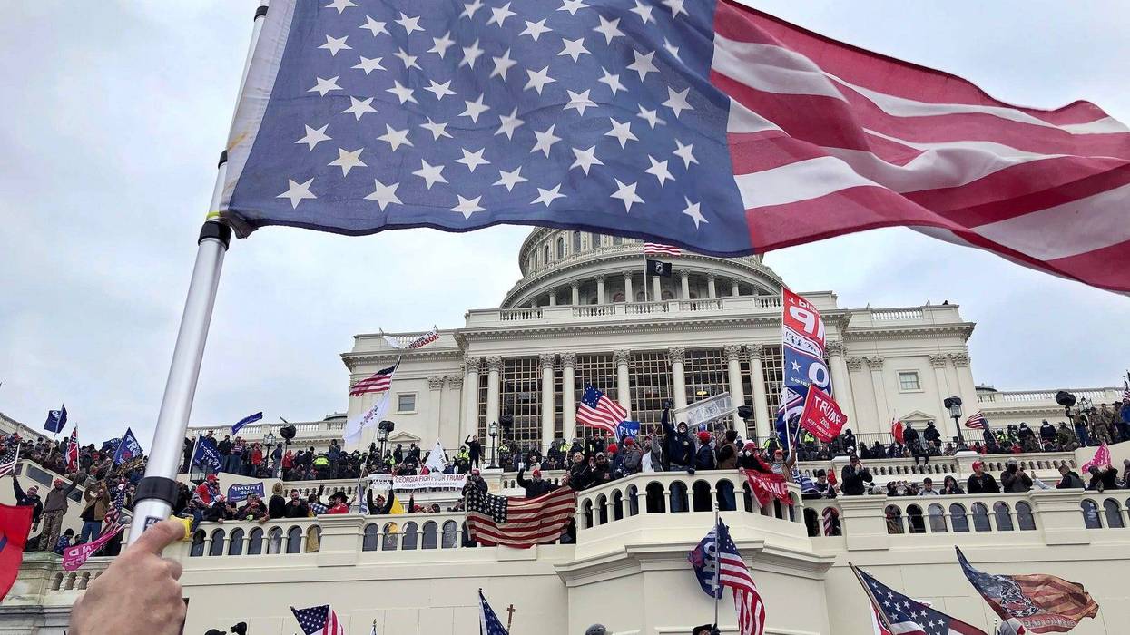 An inverted American flag waves over the pro-Trump mob that took over the steps of the Capitol in Washington, DC, Wednesday, January 6, 2021 Capitol Takeover