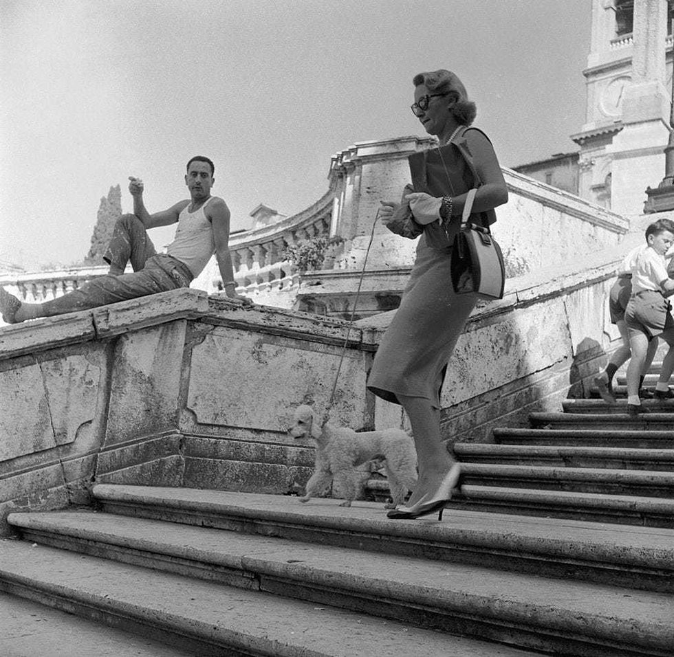An Italian labourer watches an American tourist walking her poodle down the Spanish Steps in Rome. (Photo by Evans/Three Lions/Getty Images)