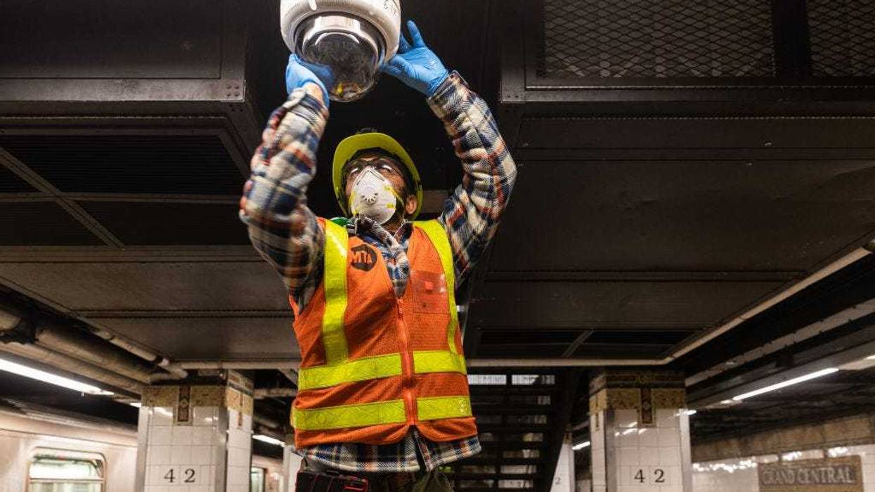 An MTA employee wearing a protective mask cleans a subway security camera at Grand Central Terminal on March 12, 2020 in New York City.