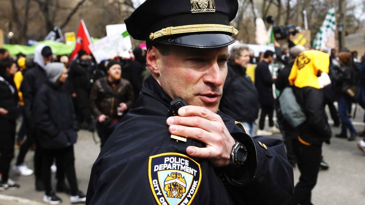An NYPD officer talks on his radio while people take part in a protest against Donald Trump, on March 19, 2016 in New York City.