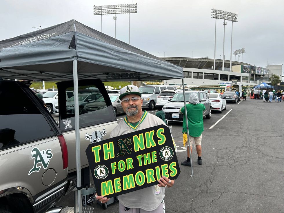 An Oakland Athletics fan holds a sign outside the Oakland Coliseum before the team