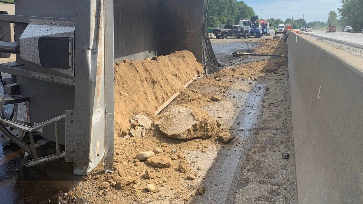 An overturned gravel hauler and hundreds of gallons of leaked fuel are hindering clean up efforts from a crash that injured two people on I-96 in Oakland County, officials say.