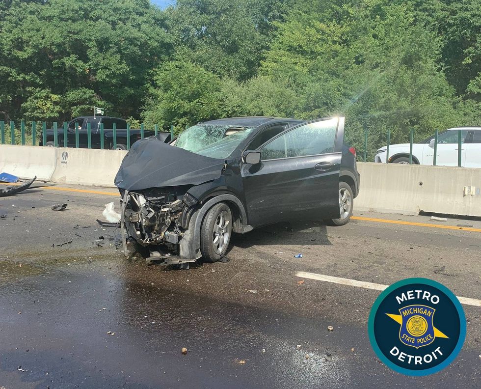 An overturned gravel hauler and hundreds of gallons of leaked fuel are hindering clean up efforts from a crash that injured two people on I-96 in Oakland County, officials say.