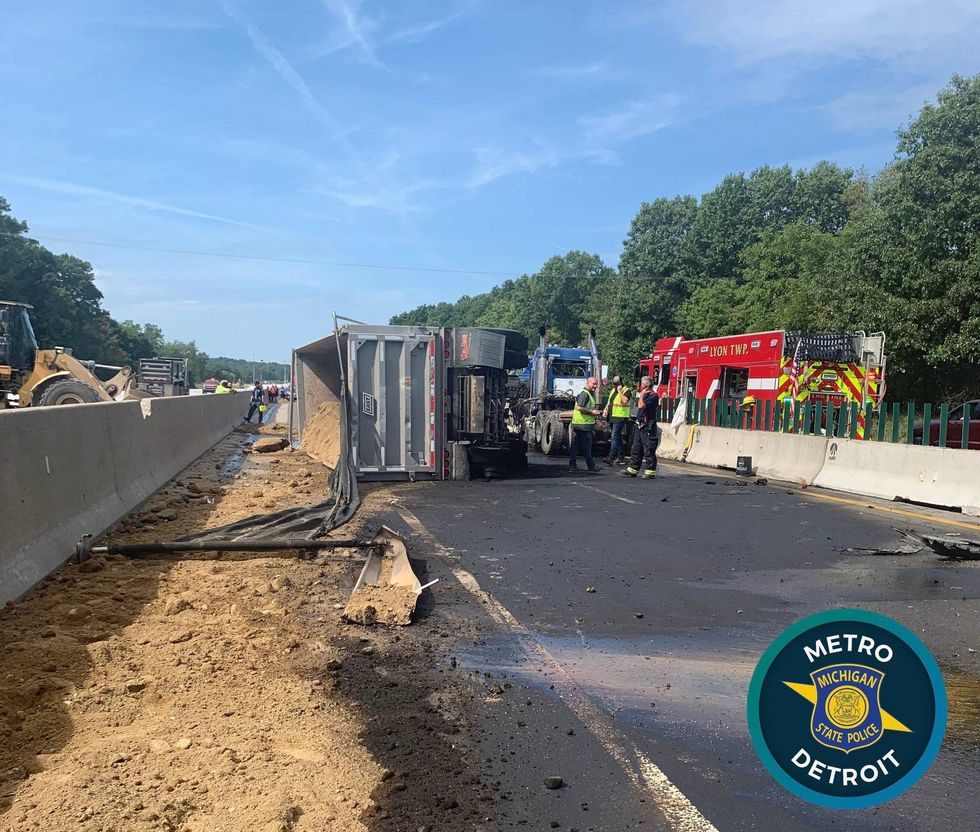 An overturned gravel hauler and hundreds of gallons of leaked fuel are hindering clean up efforts from a crash that injured two people on I-96 in Oakland County, officials say.