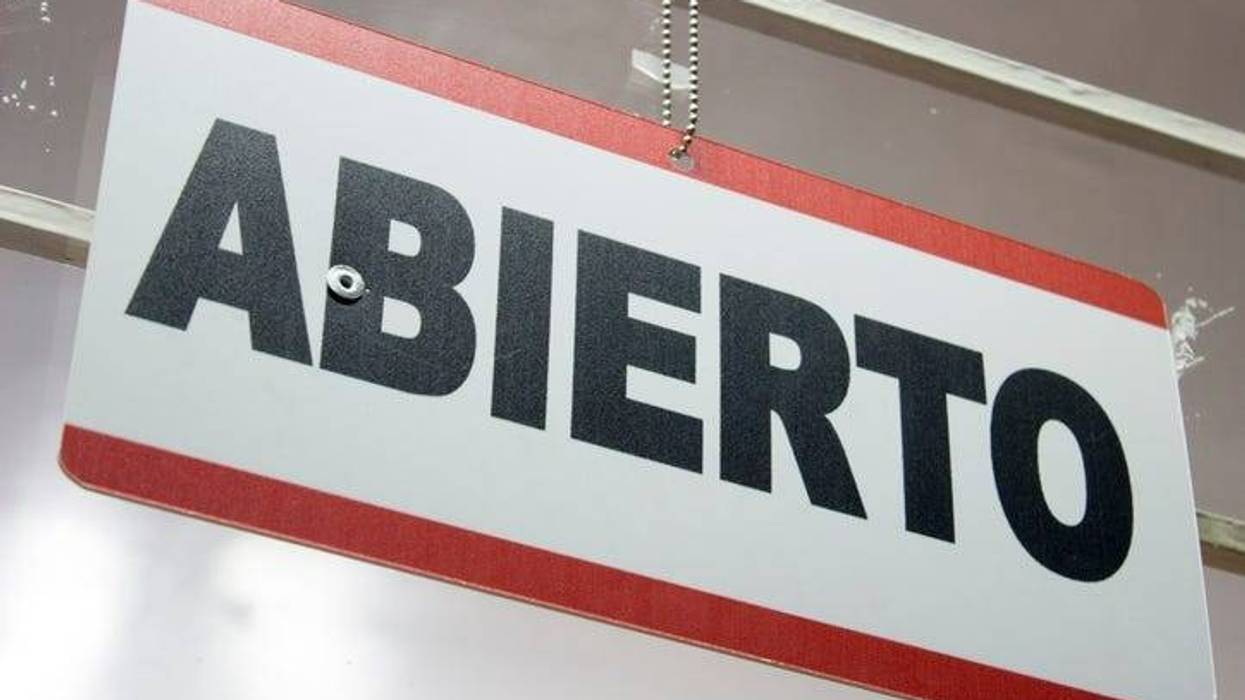 An spanish open sign hanging in a store. Abierto meaning open.