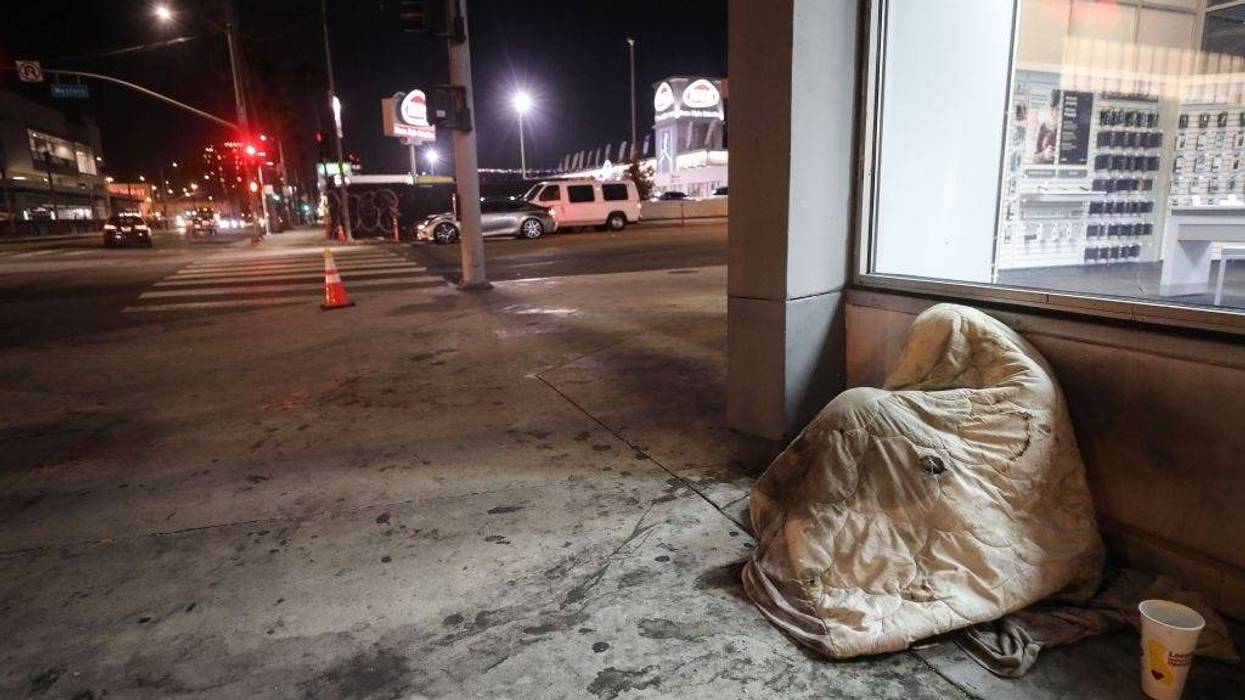 An unhoused person rests beneath a blanket on Sunset Boulevard amid the COVID-19 pandemic on July 1, 2020 in Los Angeles, California.
