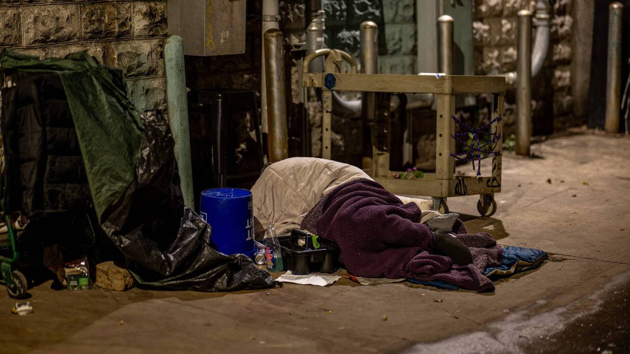 An unhoused resident sleeps in an alleyway near his cleaning supplies on Dec. 18, 2023, in Austin, Texas.