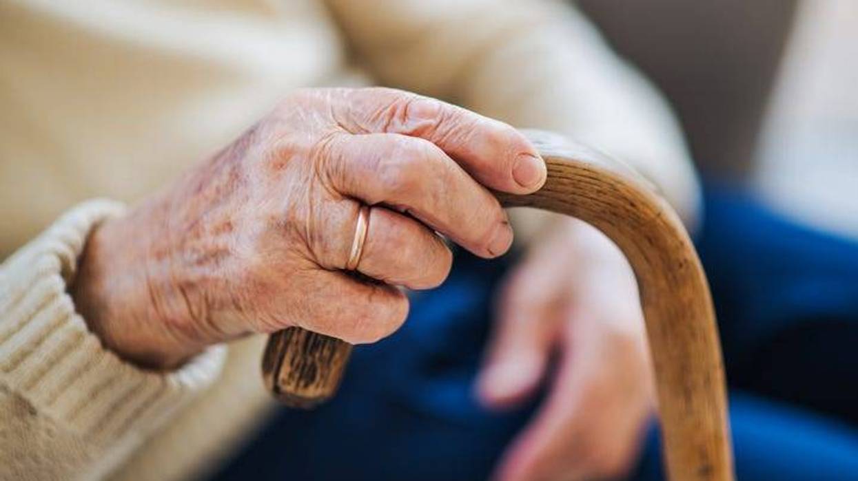 and older woman's hand holding a cane