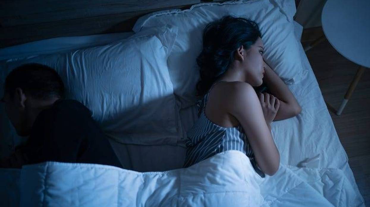 Angry woman laying in bed with husband