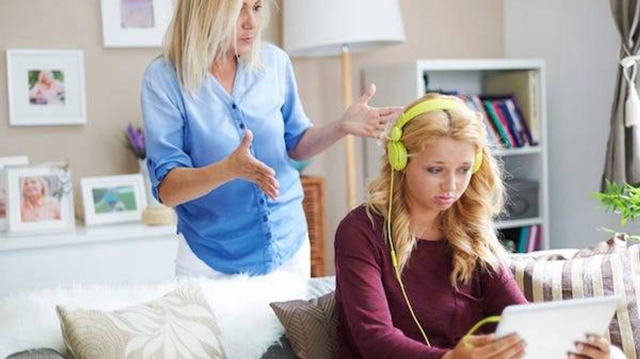 Annoyed mom looking at daughter wearing headphones