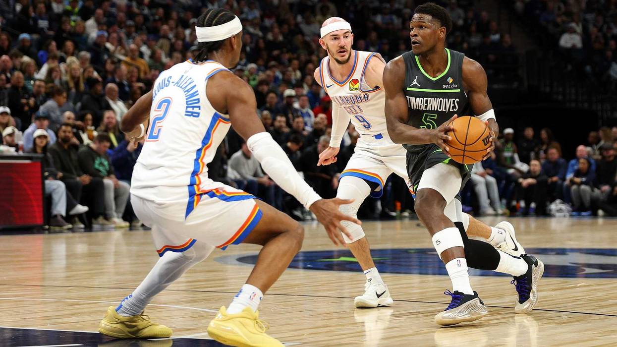 Anthony Edwards #5 of the Minnesota Timberwolves drives to the basket against Alex Caruso #9 and Shai Gilgeous-Alexander #2 of the Oklahoma City Thunder in the first quarter at Target Center on February 23, 2025 in Minneapolis, Minnesota.