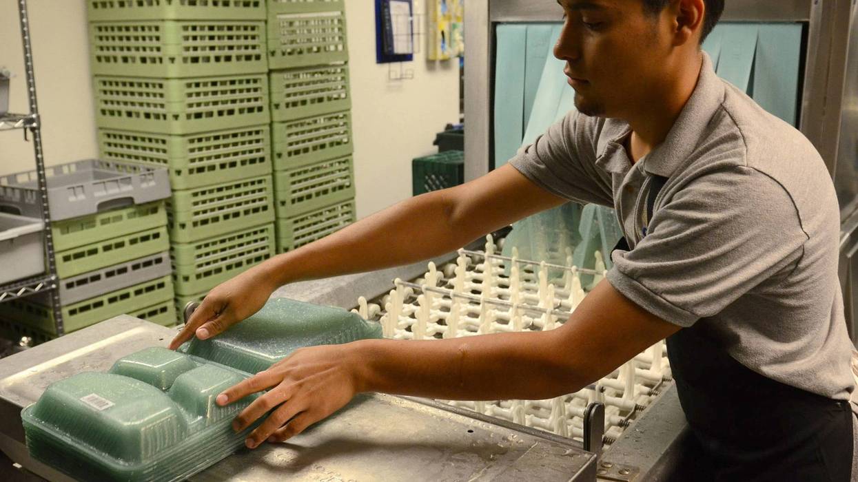 Antoni Fajaro, student from Los Angeles, washes re-usable go containers that students used to fill with food, then they are inserted into the OZZI machine which refunds the $5 deposit on the tray.