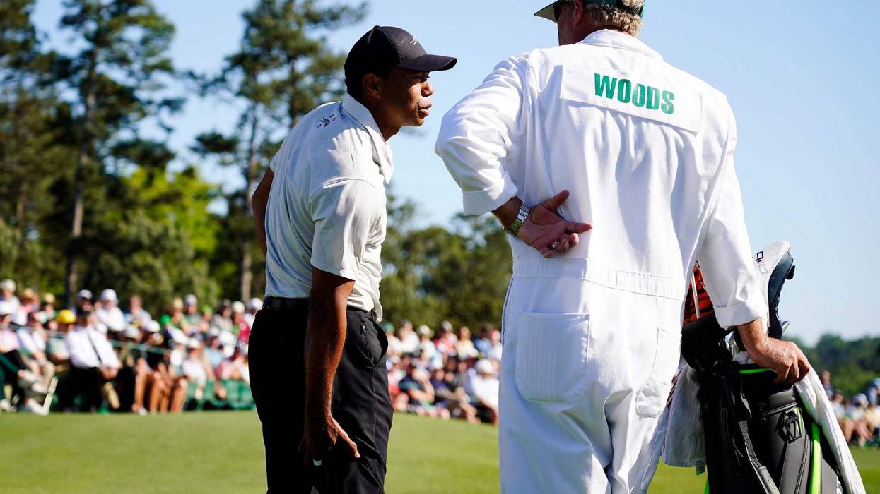 Apr 13, 2024; Augusta, Georgia, USA; Tiger Woods talks with his caddie Lance Bennett while holding the back of his leg on the No. 18 green during the third round of the Masters Tournament. Mandatory Credit: Katie Goodale-USA TODAY Network