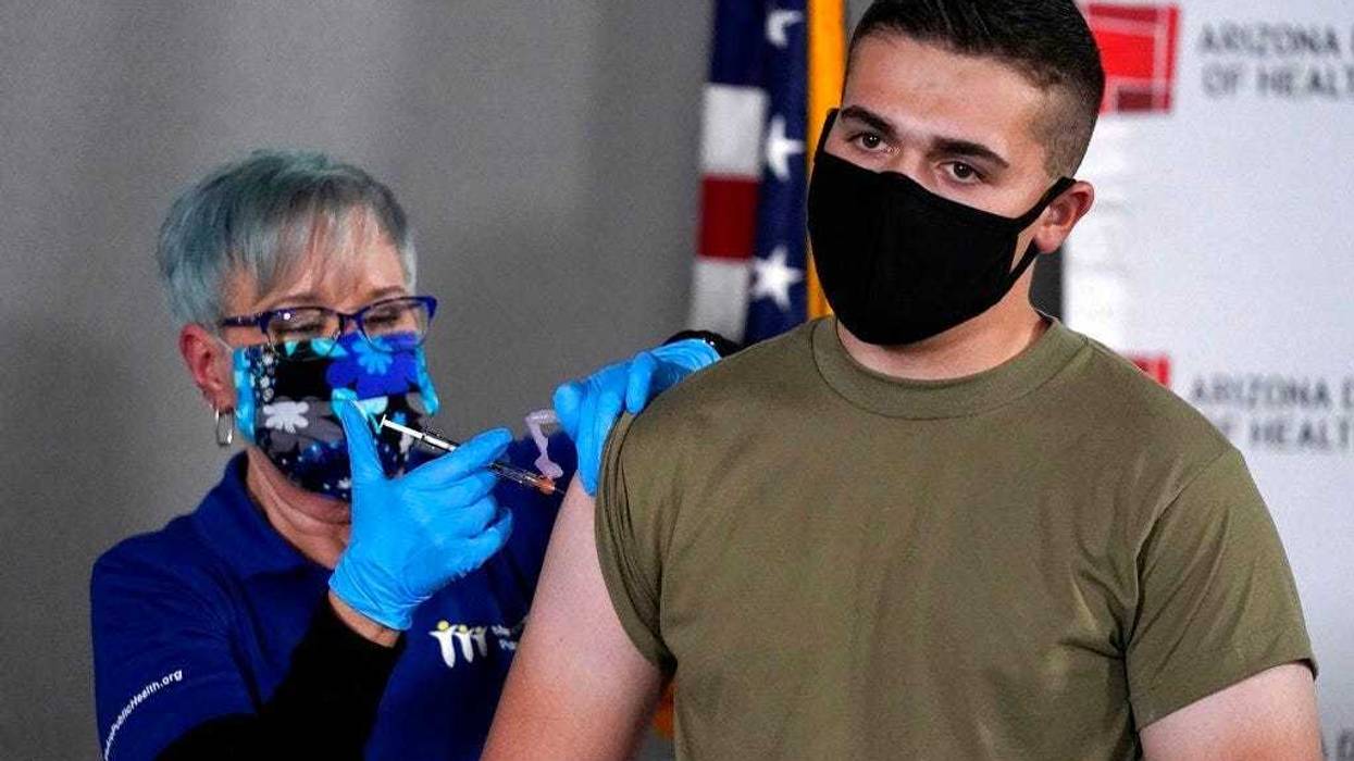 Arizona Air National Guard medic Will Smith, right, receives one of the first doses of the Pfizer-BioNTech vaccine for COVID-19 at the Arizona Department of Health Services State Laboratory from nurse Machrina Leach, Wednesday, Dec. 16, 2020, in Phoenix.