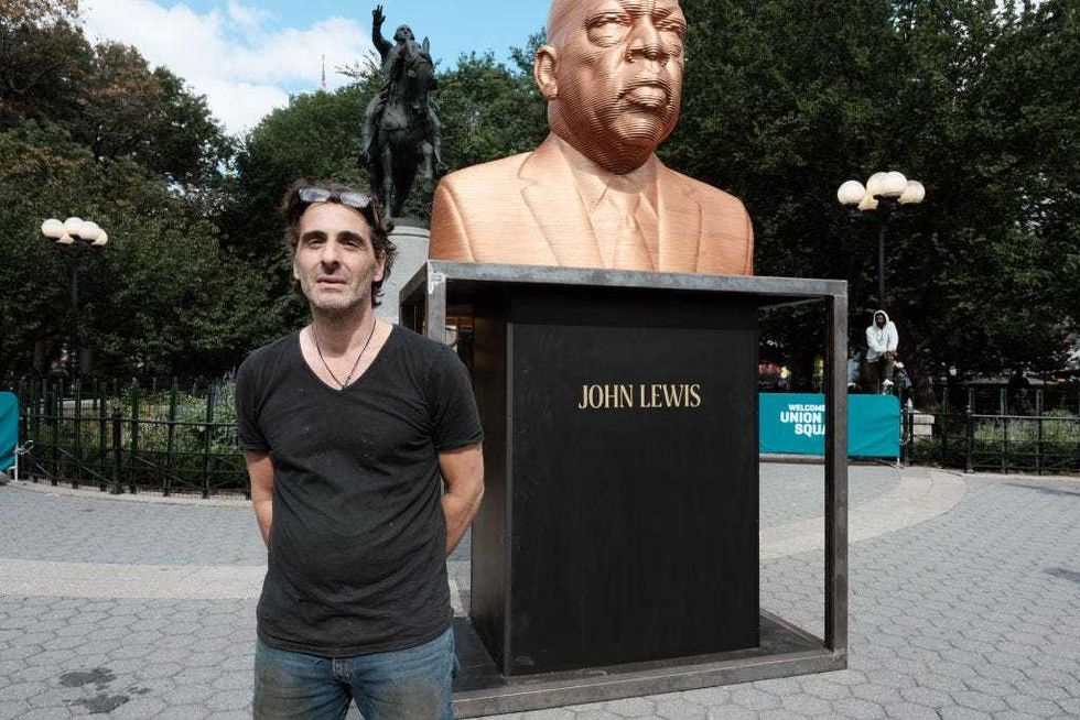 Artist Chris Carnabuci stands beside his new public art project entitled SEEINJUSTICE by the group Confront Art as it is installed in New York