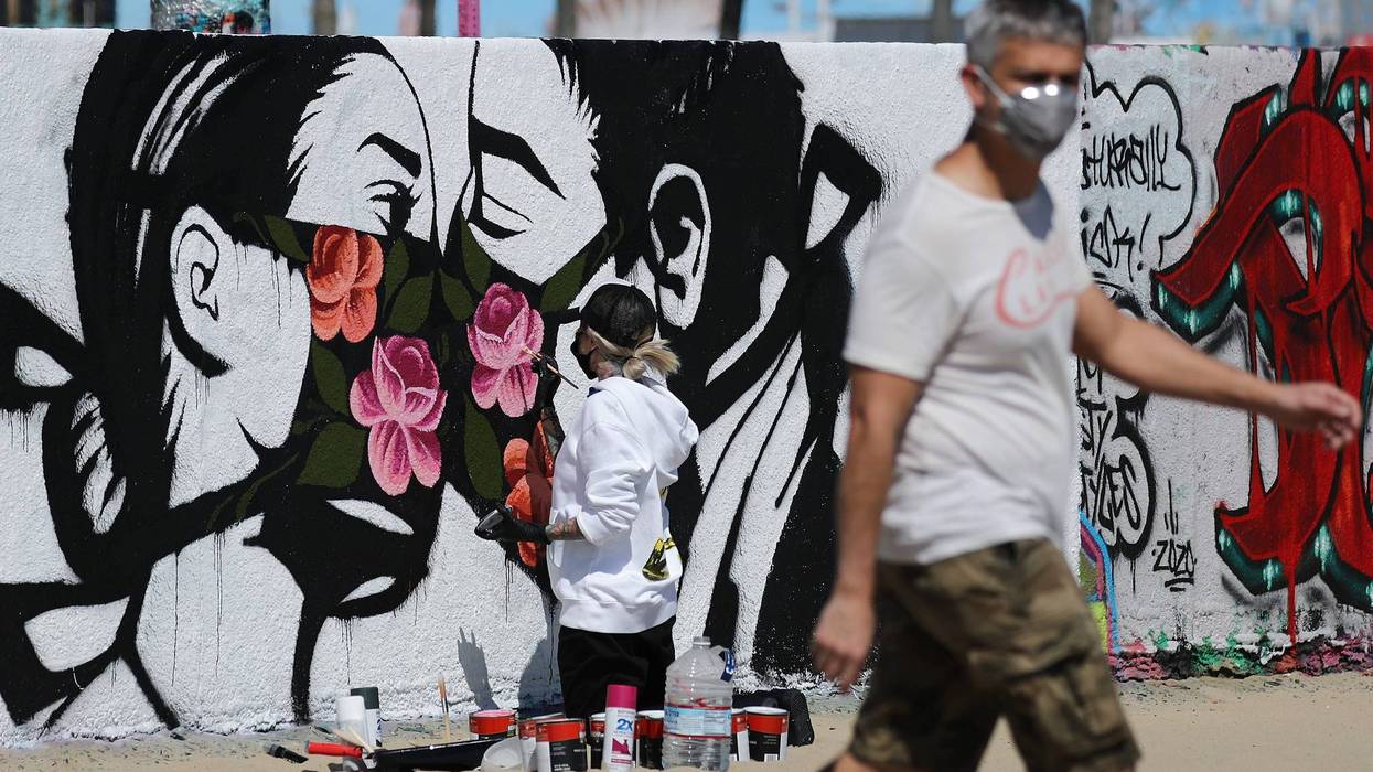 Artist Pony Wave paints a scene depicting two people kissing while wearing face masks on Venice Beach on March 21, 2020 in Venice.