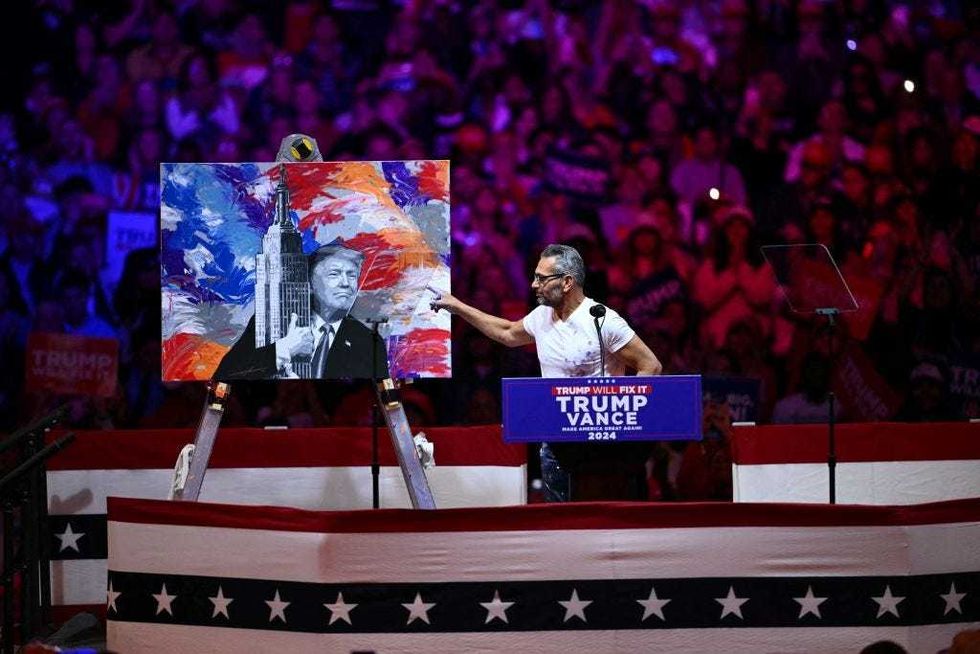Artist Scott LoBaido points to his portrait of former US president and Republican presidential candidate Donald Trump during a campaign rally at Madison Square Garden in New York on Oct. 27, 2024.