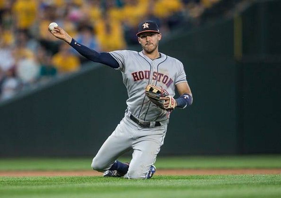 Astros SS Carlos Correa makes a throw from his knees.
