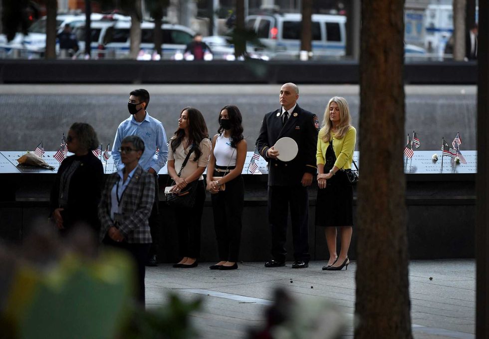 Attendees listen to the U.S. National Anthem at the National 9/11 Memorial as they take part in a ceremony commemorating the 20th anniversary of the 9/11 attacks on the World Trade Center on September 11, 2021 in New York City.