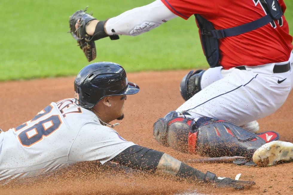 Aug 16, 2022; Cleveland, Ohio, USA; Detroit Tigers shortstop Javier Baez (28) scores beside Cleveland Guardians catcher Austin Hedges (17) in the first inning at Progressive Field.