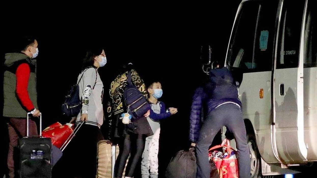 Australian evacuees board a bus after arriving at the airport on Christmas Island, Australia, early Thursday, Feb. 6, 2020. The evacuees left Wuhan, China, on an Air New Zealand rescue flight Wednesday.
